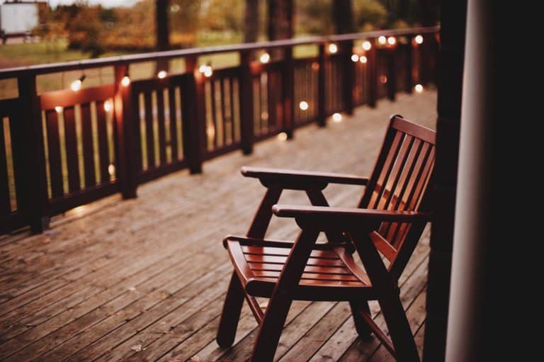 Wooden deck at dusk with small lights along the railing and a chair