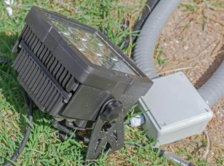 Outdoor LED flood light and a junction box with conduit on the grass