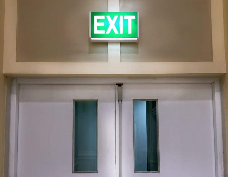 Illuminated EXIT sign mounted above a pair of white doors
