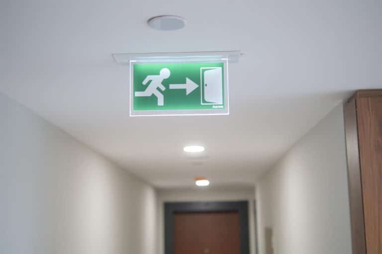 Hallway with a lit exit sign hanging from the ceiling