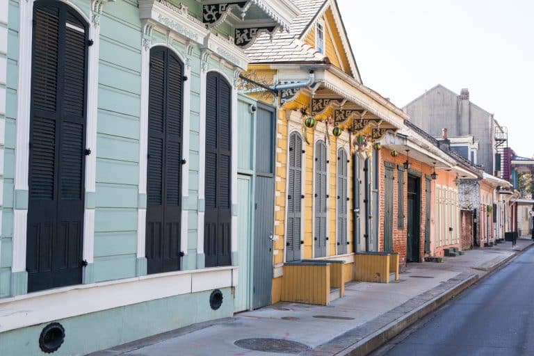 Colourful New Orleans shotgun houses with shutters and wall-mounted gallery lanterns