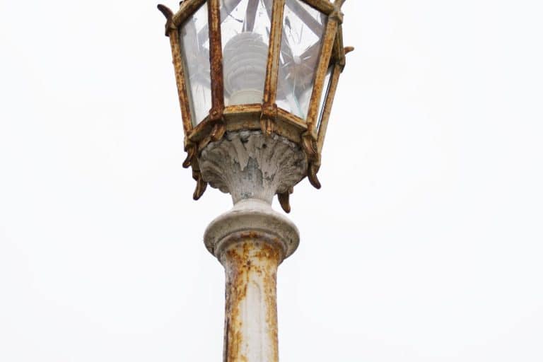 Weathered outdoor lamp head with rust and peeling paint