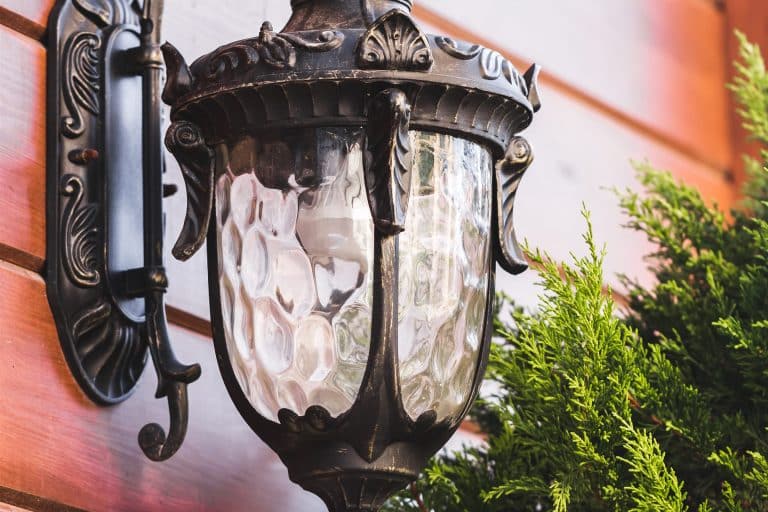 Wall-mounted outdoor lantern fixture and its bracket on a wood wall
